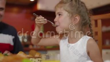 快乐的女孩和她的家人在同一张桌子上吃饭。 在家庆祝节日。 全家围桌吃饭